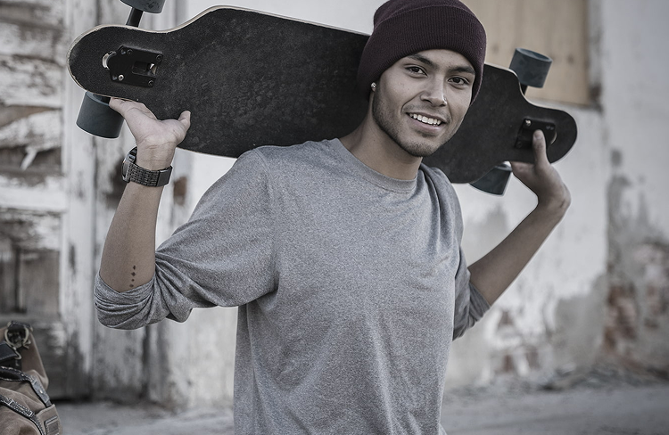 Joven sosteniendo una patineta sobre el hombro
