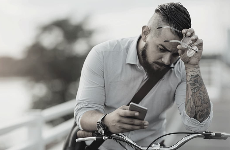 Hombre sentado mirando su teléfono con expresión pensativa