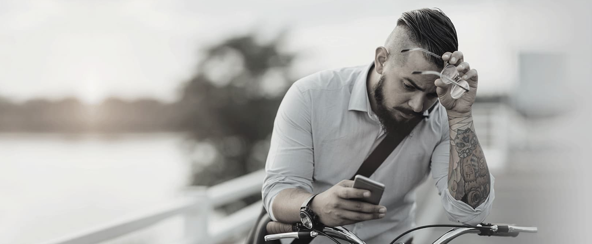 Hombre sentado mirando su teléfono con expresión pensativa